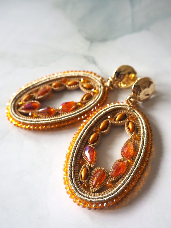 Leuke opvallende oorbellen van brass stekers met oranje kristal en gouddraad.